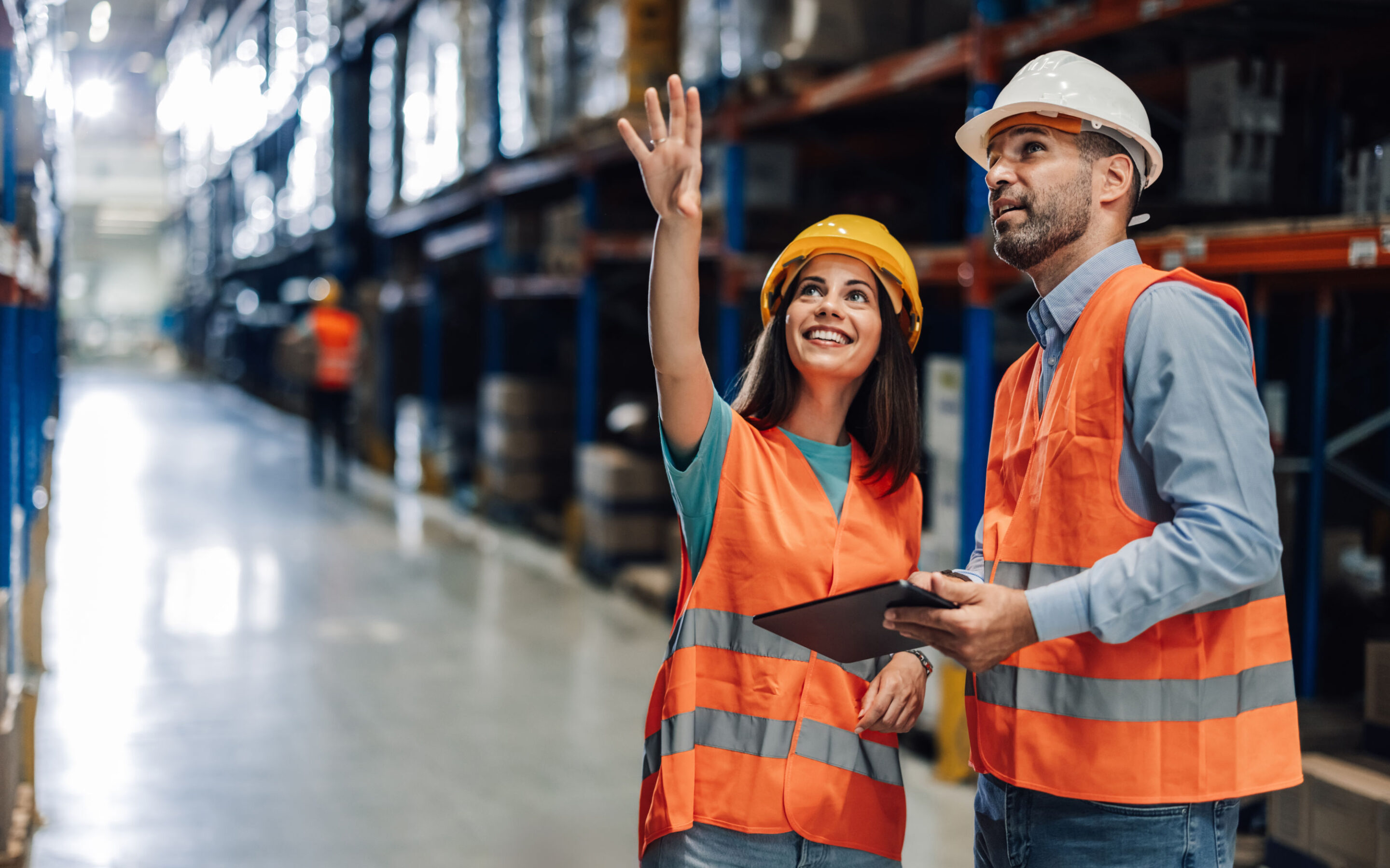 Two Warehouse Workers Wearing Safety Vests Are Discussing Logistics While