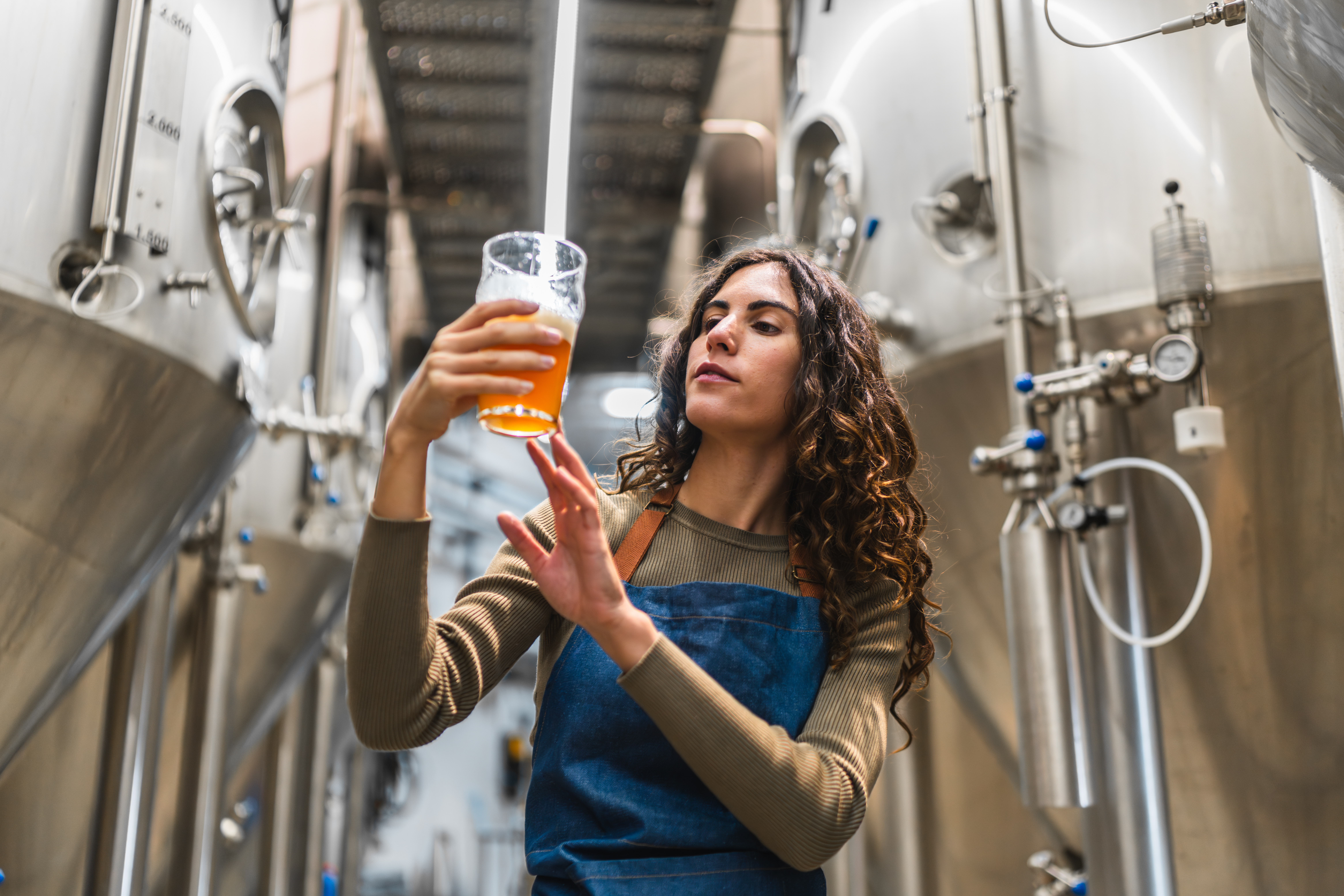 Woman brewmaster inspecting craft beer quality in brewery