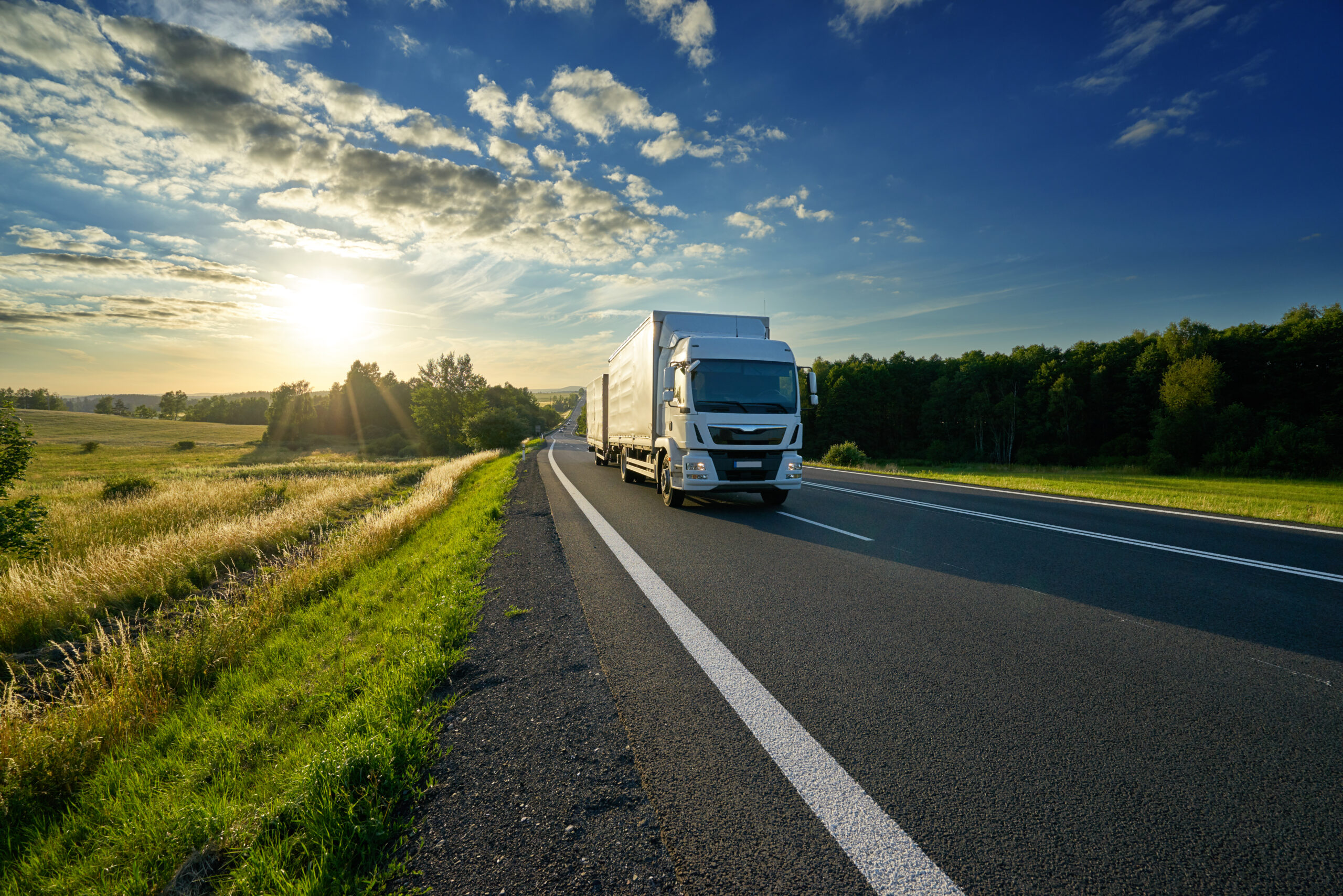 White delivery truck driving on the asphalt road Kühl-LKW rollt über die Grenze zur Abfüllanlage